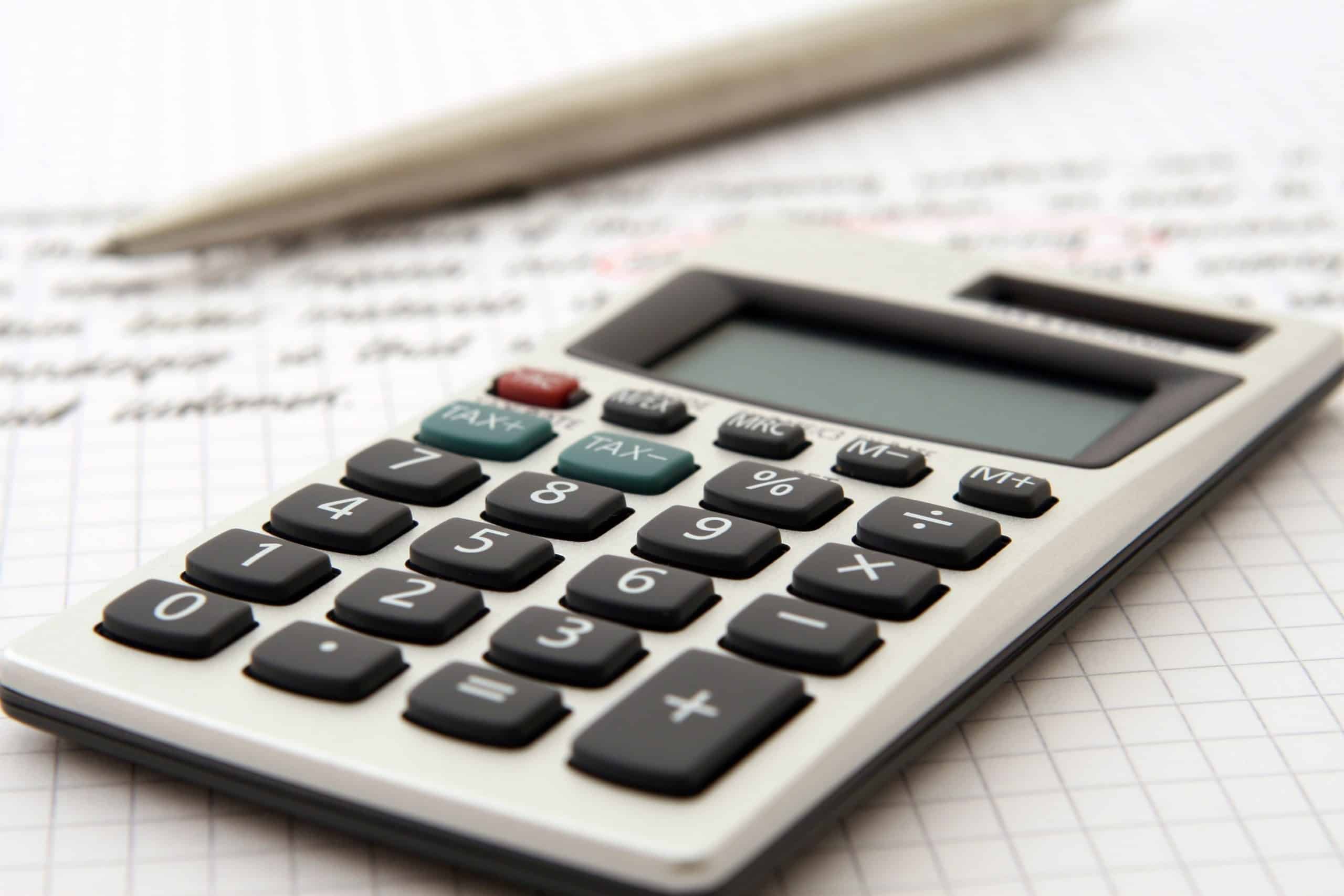 A calculator and a pen placed on a sheet of graph paper with handwritten notes outlining the employee turnover rate.